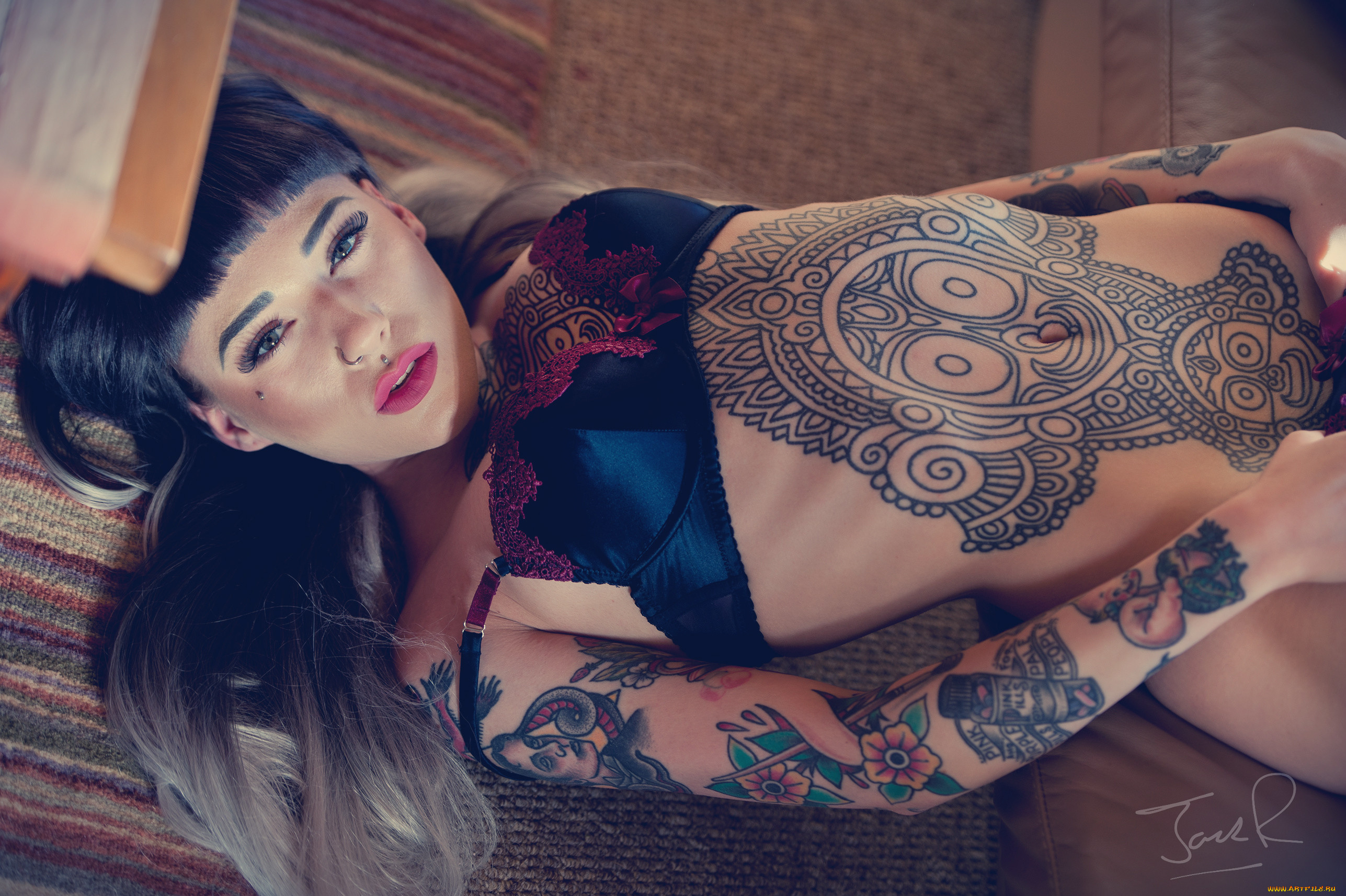 Молодая брюнетка с татуировками на теле показывает стриптиз