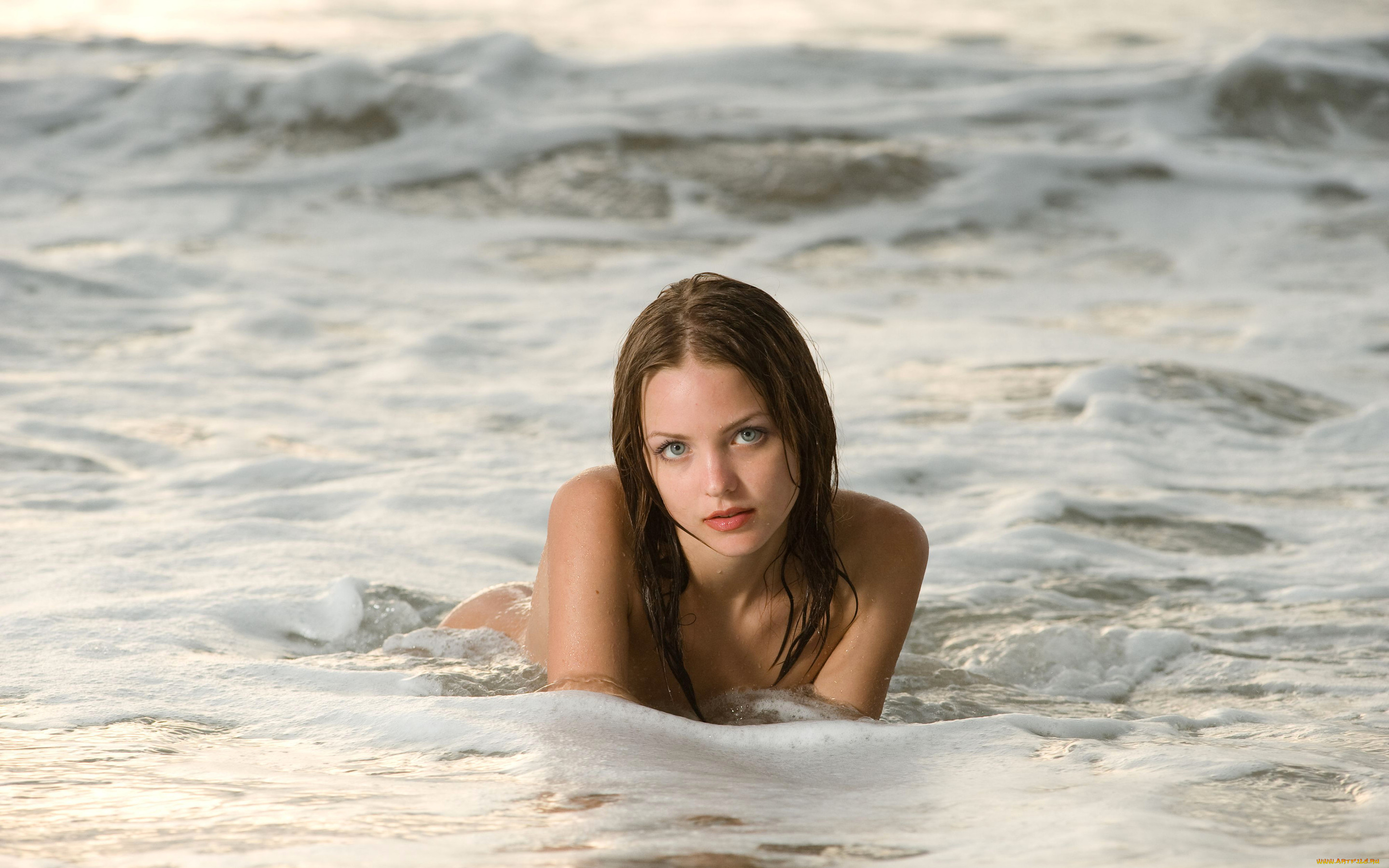 Молодая обнажённая девушка на берегу моря